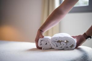 een persoon legt handdoeken op een bed bij Hôtel - Restaurant U Santu Petru in Saint-Florent