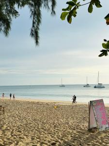 een bord op een strand met boten in het water bij Lanta L.D. Beach Bungalow in Koh Lanta