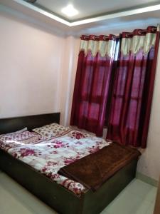 a bedroom with a bed with red curtains at Hotel Hansa Palace by WB Inn in Kānpur