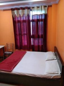 a bed in a room with red curtains at Hotel Hansa Palace by WB Inn in Kānpur
