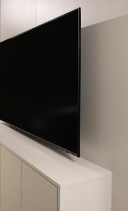 telewizor z płaskim ekranem siedzący na białej szafce w obiekcie Apartamenty Legionów 40 - A12 w Kaliszu