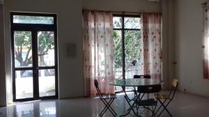 een eetkamer met een tafel, stoelen en ramen bij Tic Guest House in Liên Trì (3)