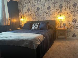 ein Schlafzimmer mit einem Bett und einer Tapetenwand in der Unterkunft Bwthyn Rhosyn Bach in Henllan