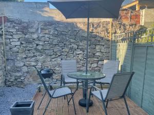 une table et des chaises avec un parasol sur une terrasse dans l'établissement Bwthyn Rhosyn Bach, à Henllan