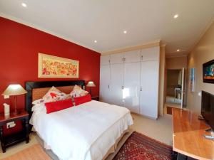 a bedroom with a large white bed with red walls at Luxury Villa in Pinnacle Point with Inverter in Mossel Bay