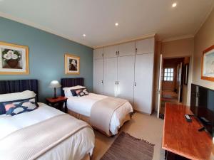 1 dormitorio con 2 camas, escritorio y TV en Luxury Villa in Pinnacle Point with Inverter en Mossel Bay