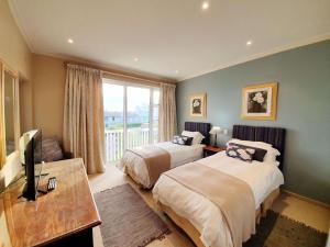 a hotel room with two beds and a television at Luxury Villa in Pinnacle Point with Inverter in Mossel Bay +32 photos