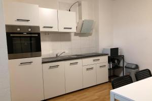kuchnia z białymi szafkami i zlewem w obiekcie cozy Apartments with WiFi w mieście Oberhausen