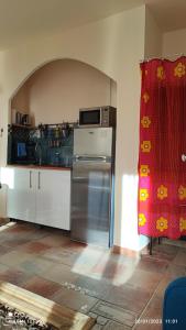 een keuken met een koelkast en een rood gordijn bij Petit cocon à Mourepiane in Marseille