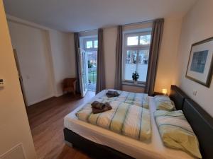una camera da letto con un grande letto con due finestre di Villa Schönfeld Wohnung 1 a Papenburg