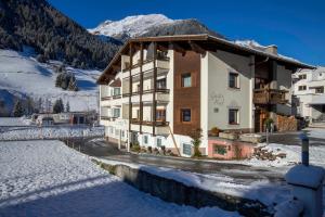 un grand bâtiment dans la neige avec une montagne dans l'établissement Gidis Hof, à Ischgl