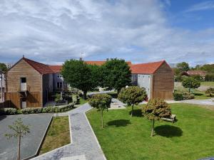 a park with houses and trees and a bench at Le Village du Phare in Gouville-sur-Mer