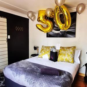 um quarto com uma cama com balões de ouro em The Fellows Guest Accommodation em Postmasburg