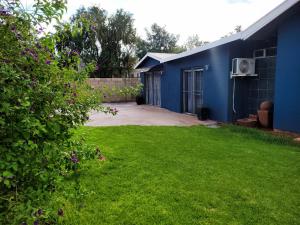 a yard with a blue house and a yard at The Fellows Guest Accommodation in Postmasburg