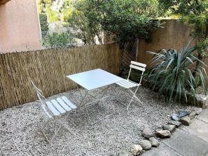 a white table and two chairs in front of a fence at Appartement rénové à Cavalière avec terrasse in Le Lavandou