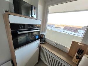a kitchen with a microwave oven and a window at Ferienwohnung Seestern Geeste in Bremerhaven