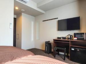 een hotelkamer met een bed en een bureau met een televisie bij HOTEL LiVEMAX Akasaka GRANDE in Tokyo