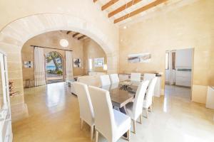 a dining room with a table and white chairs at Villa Es Morer in Alcudia