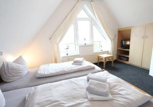 2 Betten in einem Zimmer mit einem großen Fenster in der Unterkunft Karkpolder Residenz Haus 3 in Langeoog