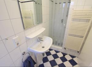 a white bathroom with a sink and a mirror at Karkpolder Residenz Haus 3 in Langeoog