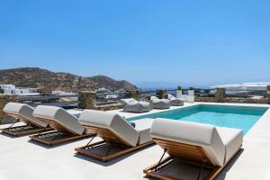 a row of lounge chairs next to a swimming pool at Roca Bonita villa in Elia Beach