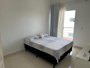 a bed in a white room with a window at Minha casa, sua casa in Porto Seguro