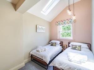 two beds in a room with a window at Northdene - 5 star Lake District Cottage in Cockermouth