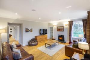 a living room with leather furniture and a fireplace at Greenmyre Farmhouse with Hot Tub in Kirriemuir