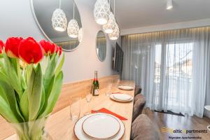 a dining room with a table with red tulips at Baltic Apartments - Matejki 17 in Świnoujście