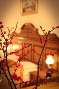 a tree branch with red berries in front of a bed at Kemencés Csárda és Panzió in Hajdúszoboszló