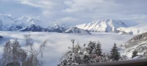 Blick auf eine schneebedeckte Bergkette mit Wolken in der Unterkunft Studio montagnard vue splendide ALPE D HUEZ LES PASSEAUX in L'Alpe-d'Huez