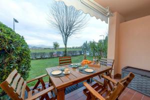 une table et des chaises en bois sur une terrasse avec un arbre dans l'établissement Casa Esmeralda, à Polpenazze del Garda