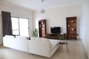 ein Wohnzimmer mit einem weißen Sofa und einem TV in der Unterkunft Seaview 3 bedroom apartment in Sliema in Sliema