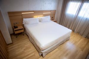 um quarto com uma grande cama branca e uma janela em Sercotel Gran Fama em Almería