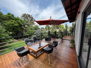 una terraza con mesa, sillas y sombrilla en Panorama Guest House en Johannesburgo