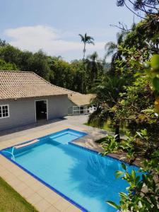 a blue swimming pool in front of a house at Chácara Misfav capacidade de 200 pessoas in Mogi das Cruzes