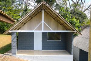 a small shed with a pitched roof and a white door at Chácara Misfav capacidade de 200 pessoas in Mogi das Cruzes