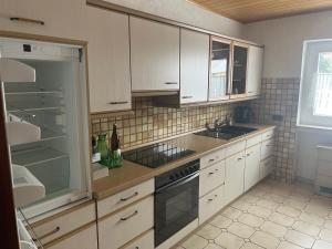 a kitchen with white cabinets and a sink and a stove at Ferienwohnungjahrsfeld in Straßenhaus