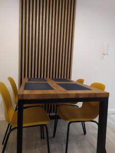 a dining room table with yellow chairs around it at Apartament FOCUS DUO in Gdańsk