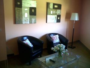 2 sillas en una sala de estar con mesa y flores en Apartamentos Rurales de Abelleira, en Muros