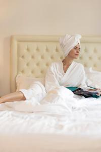 Hôtel Nice Azur Riviera في نيس: امرأة مستلقية على السرير تقرأ كتابا
