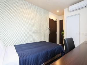 HOTEL LiVEMAX Asakusa Sky Front في طوكيو: غرفة نوم بسرير وطاولة مع كرسي