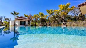 a swimming pool with blue water and palm trees at Isan Golf & Adventure Hotel in Udon Thani