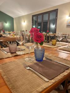 una mesa con copas de vino y una rosa en un jarrón en MANZIL Country House, en Valderice