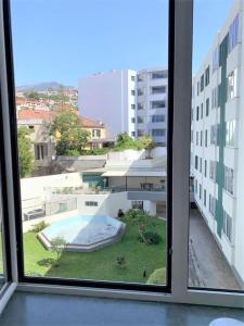 uma vista para uma piscina a partir de uma janela num edifício em Madeira, 3 bedroom apartment with ocean views in Funchal no Funchal