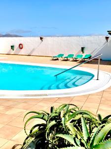 a swimming pool with lounge chairs in a building at Relax Tiñosa Apartment in Puerto del Carmen