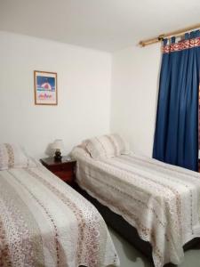 2 camas en una habitación con cortina azul en La Serena Viajes, en La Serena