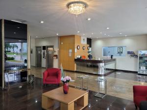 a lobby with a red chair and a vase of flowers on a table at Hotel Dan Inn São José dos Campos in São José dos Campos