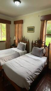 two beds in a bedroom with two windows at Kwezi Cottage at The Great Rift Valley Lodge & Golf Resort Naivasha in Naivasha