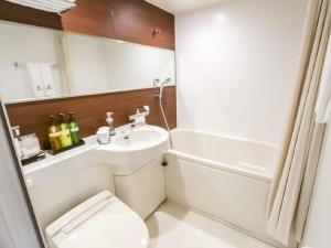 a bathroom with a toilet and a sink and a tub at HOTEL LiVEMAX Hachioji Ekimae in Hachioji